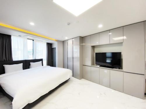 a bedroom with a white bed and a flat screen tv at Songjeong Blue Castle Hotel in Busan