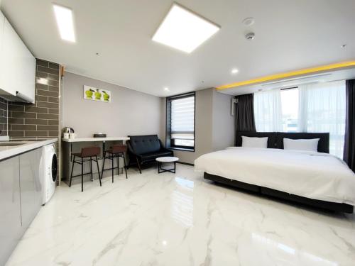 a bedroom with a large bed and a kitchen at Songjeong Blue Castle Hotel in Busan