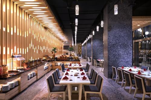 a dining room with tables and chairs in a restaurant at Grand Mercure Jakarta Kemayoran in Jakarta