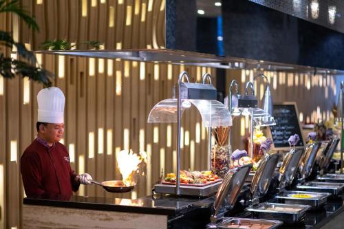 a chef standing in front of a buffet line of food at Grand Mercure Jakarta Kemayoran in Jakarta