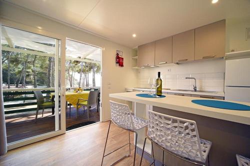 a kitchen with a counter and chairs and a table at Camping Europa in Capoliveri