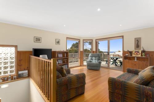 a living room with two chairs and a television at Magnolia in Apollo Bay