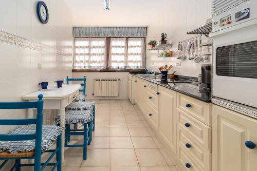 a kitchen with white cabinets and blue chairs at Exclusivo Chalet en Potes in Potes