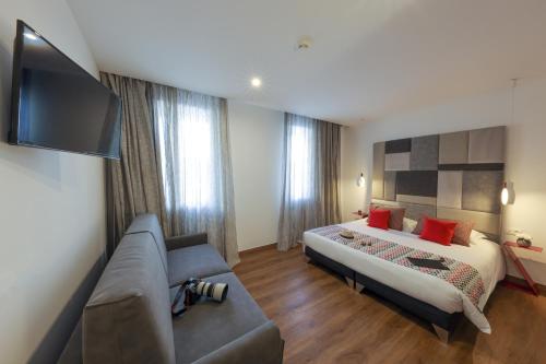 a hotel room with a bed and a couch at Hôtel Méditerranée in Calvi