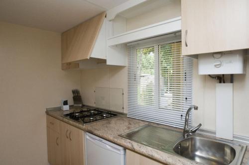 a kitchen with white cabinets and a sink and a window at Camping La Aldea in El Rocío