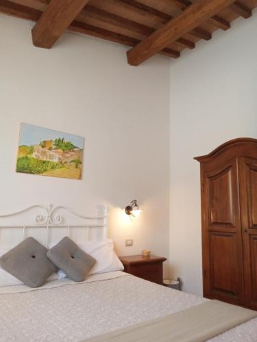 a bedroom with a white bed with a wooden headboard at I TRE POETI in Saturnia