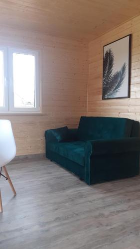 Domek wypoczynkowy nad Jez. Dadaj في بيسكوبييت: غرفة معيشة مع أريكة خضراء في غرفة