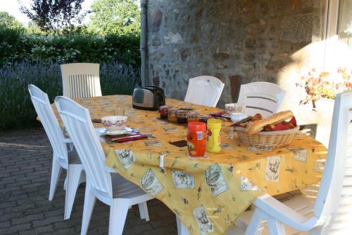a table with white chairs and a yellow table cloth at Herbages de Beauvais in Orgères-la-Roche