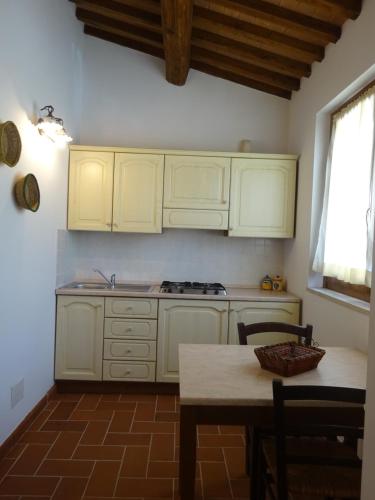 a kitchen with white cabinets and a table and a stove at I TRE POETI in Saturnia
