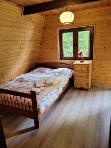 ein Schlafzimmer mit einem Bett in einem Blockhaus in der Unterkunft Słoneczna Solina in Werlas