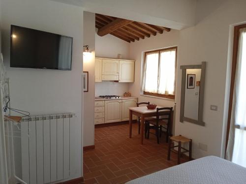 a kitchen with a table and a television on a wall at I TRE POETI in Saturnia