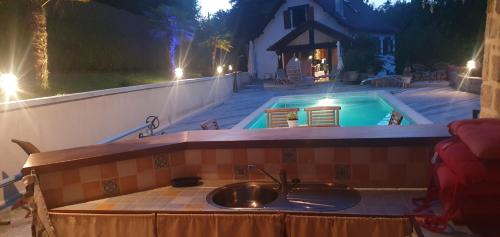 a kitchen sink and a swimming pool at night at Chambre d'hôtes un petit coin de paradis en Corrèze in Laguenne