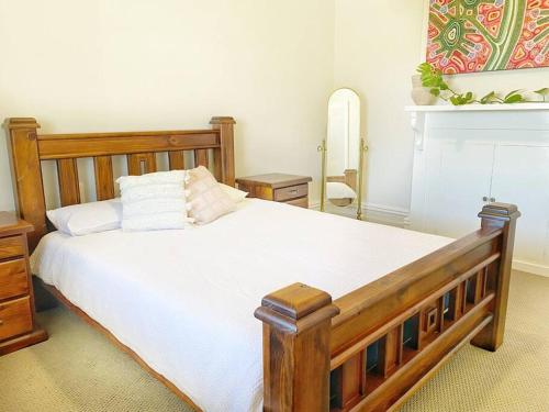 a bedroom with a large wooden bed with white sheets at The Central Cottage - Port Lincoln in Port Lincoln