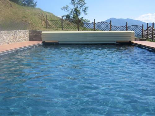 uma piscina de água azul com um banco em Casa Barile em Fosciandora