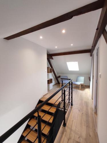 Gîte des trois châteaux في Husseren-les-Châteaux: درج في غرفة بجدران بيضاء وعوارض خشبية