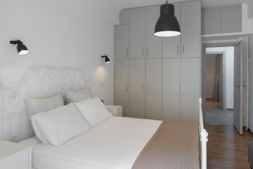 Dormitorio blanco con cama blanca y armarios blancos en Amazing apartment 2 min to Acropolis en Atenas