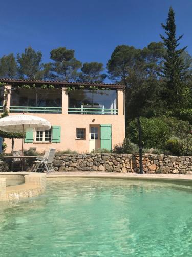 a house with a swimming pool in front of a house at Les Bosquets in Lorgues