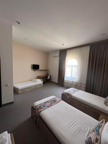 a hotel room with three beds and a television at Mahmud Hotel in Samarkand
