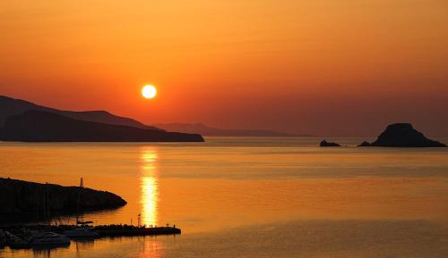 a sunset over a body of water with the sun setting at Sirokos in Karavostasi