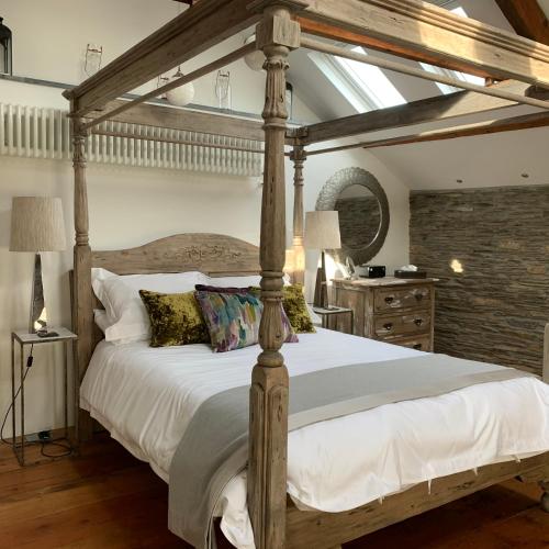 a bedroom with a canopy bed with white sheets and pillows at The Padstow Cottage - Coswarth House in Padstow