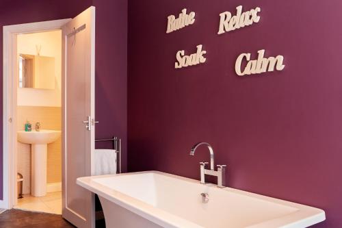 a bathroom with a white sink and a purple wall at Finest Retreats - The Pig Barn in Ashbourne