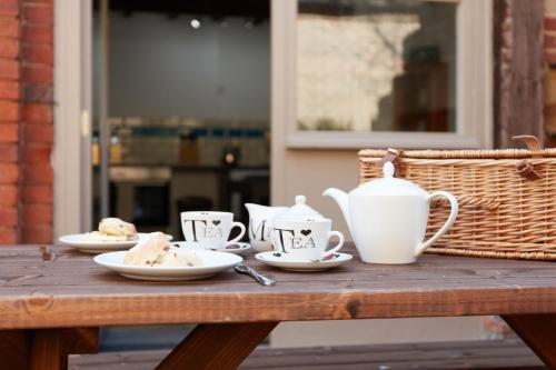 a wooden table with cups and plates of food on it at Finest Retreats - The Pig Barn in Ashbourne