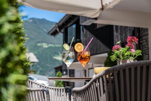 two cocktails sitting on a table on a balcony at Vitaurina Royal Hotel in Molini di Tures
