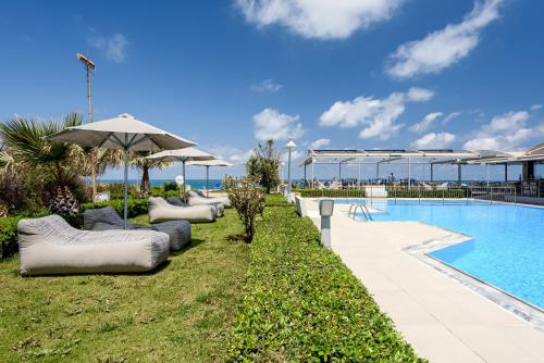 een zwembad met ligstoelen en een parasol bij Marinos Beach Hotel in Platanes