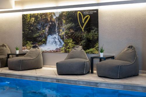 a swimming pool with chairs and a picture of a waterfall at Vitaurina Royal Hotel in Molini di Tures