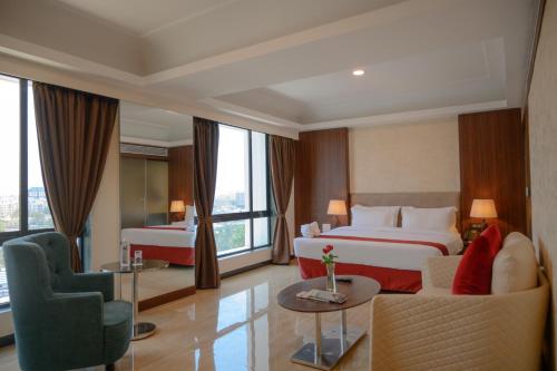 um quarto de hotel com duas camas e um sofá em Hotel Tip Top International Pune em Pune