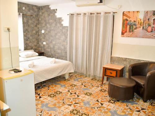 a bedroom with a bed and a chair and a couch at Vitrage Guest House in Nazareth