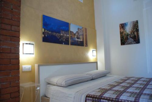 a bedroom with a bed with three pictures on the wall at Appartamento Astrea in Syracuse