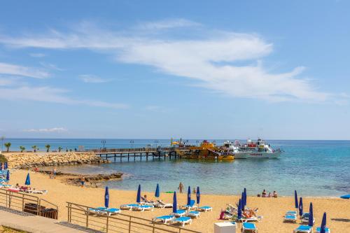 a beach with chairs and a boat in the water at Villa Nora in Protaras