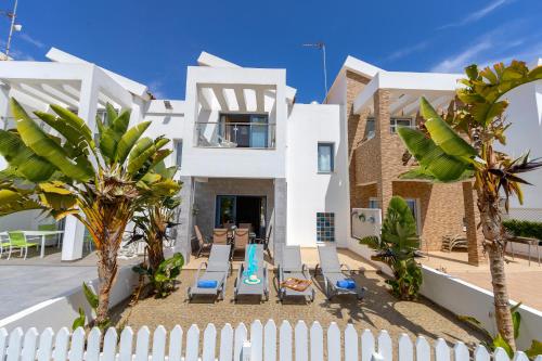 a white house with a white fence and palm trees at Villa Nora in Protaras