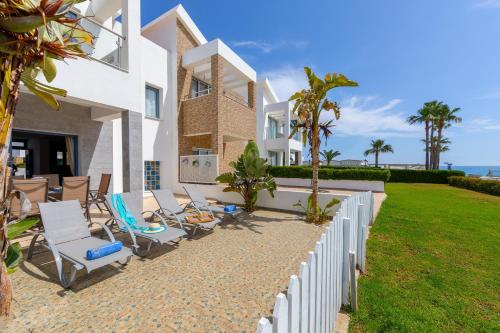 a white house with chairs and a fence at Villa Nora in Protaras
