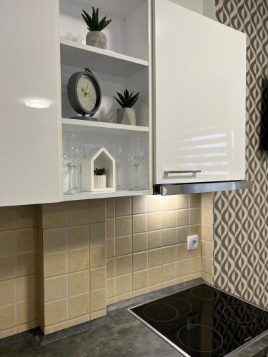 a kitchen with white cabinets and a clock on a shelf at Centar NS2 in Novi Sad