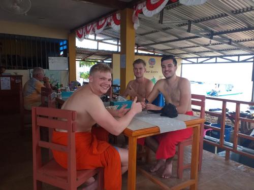 three shirtless men sitting at a table at a restaurant at 4 Sisters Divers in Bunaken