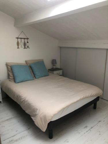 a bedroom with a large bed with blue pillows at Appartement Arc en Ciel in Châtelaillon-Plage