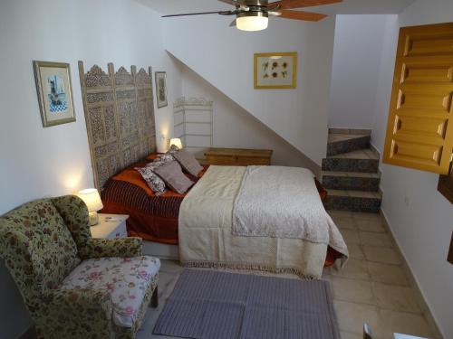 a bedroom with a bed and a chair and stairs at Casa Margarita Charming Character Cottage in Bedar, Andalusia in Bédar