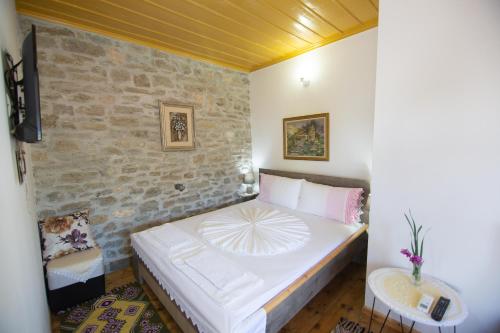 a small bedroom with a bed and a stone wall at The Mosaic House - Shtepia me Mozaik in Përmet