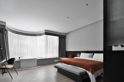 a bedroom with a bed and a desk and a tub at LIA Hotel Shenzhen Qianhai Baoan Center Turnaround Metro Station in Bao'an