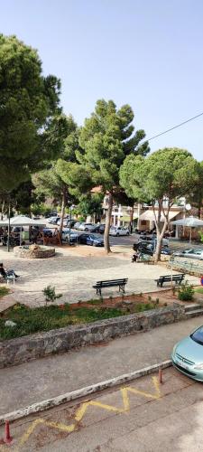 a park with benches and parked cars in a parking lot at Skardamoula's Studios n Apartments in Kardamili