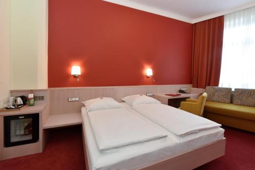 a hotel room with two beds and a couch at Hotel ADRIA München in Munich