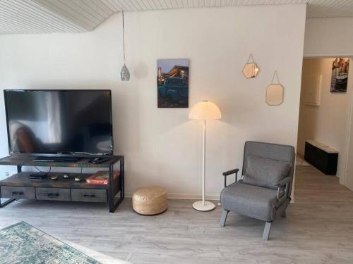ein Wohnzimmer mit einem Fernseher, einem Stuhl und einer Lampe in der Unterkunft Sand & Soul in Scharbeutz