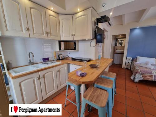 een keuken met witte kasten en een houten tafel bij I Love Perpignan Apartments 10 in Perpignan