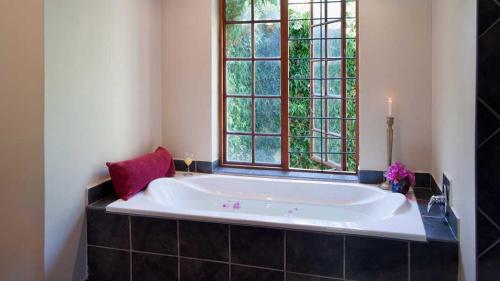 a large bath tub in a bathroom with a window at Thorntree Country Lodge in Oudtshoorn