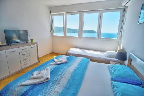 a bedroom with a bed and a tv and windows at Lala in Herceg-Novi
