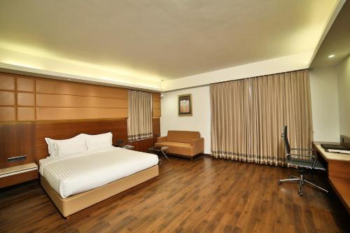 a hotel room with a bed and a desk at HOTEL G EXPRESS Formerly Known as TGB Express in Ahmedabad