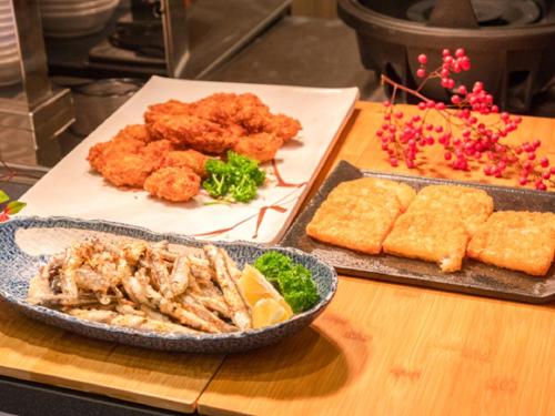 a table with a plate of food with chicken and other foods at LiVEMAX RESORT Miyahama Ocean View in Hatsukaichi