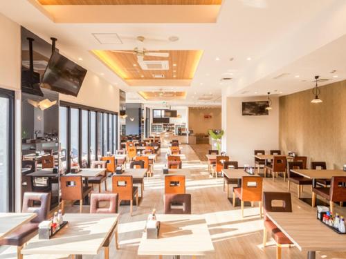 a dining room with tables and chairs and windows at LiVEMAX RESORT Miyahama Ocean View in Hatsukaichi
